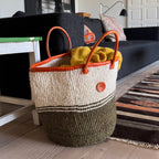 Woven basket with orange handles on a wooden floor in a living room.