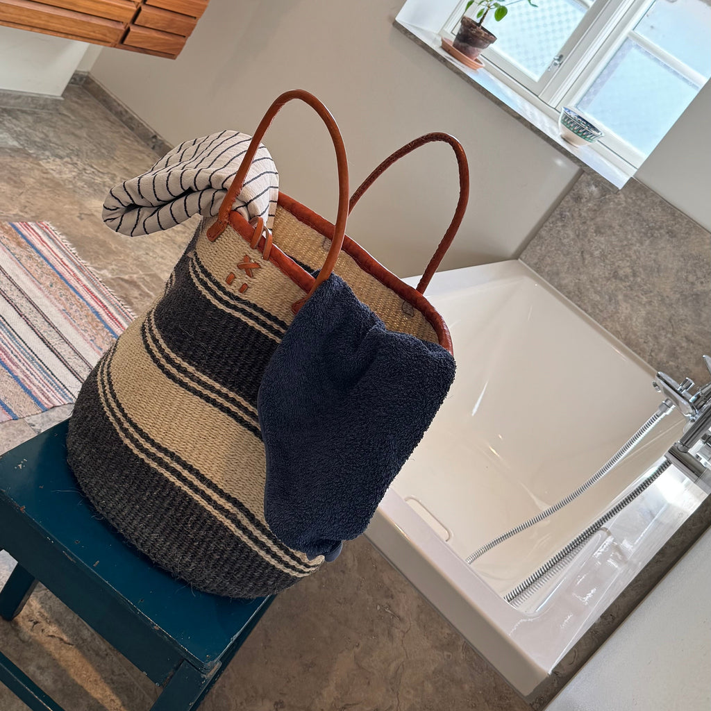 Bathroom with a woven bag on a stool, sink, and window.