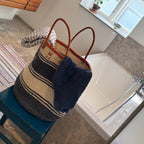 Bathroom with a woven bag on a stool, sink, and window.