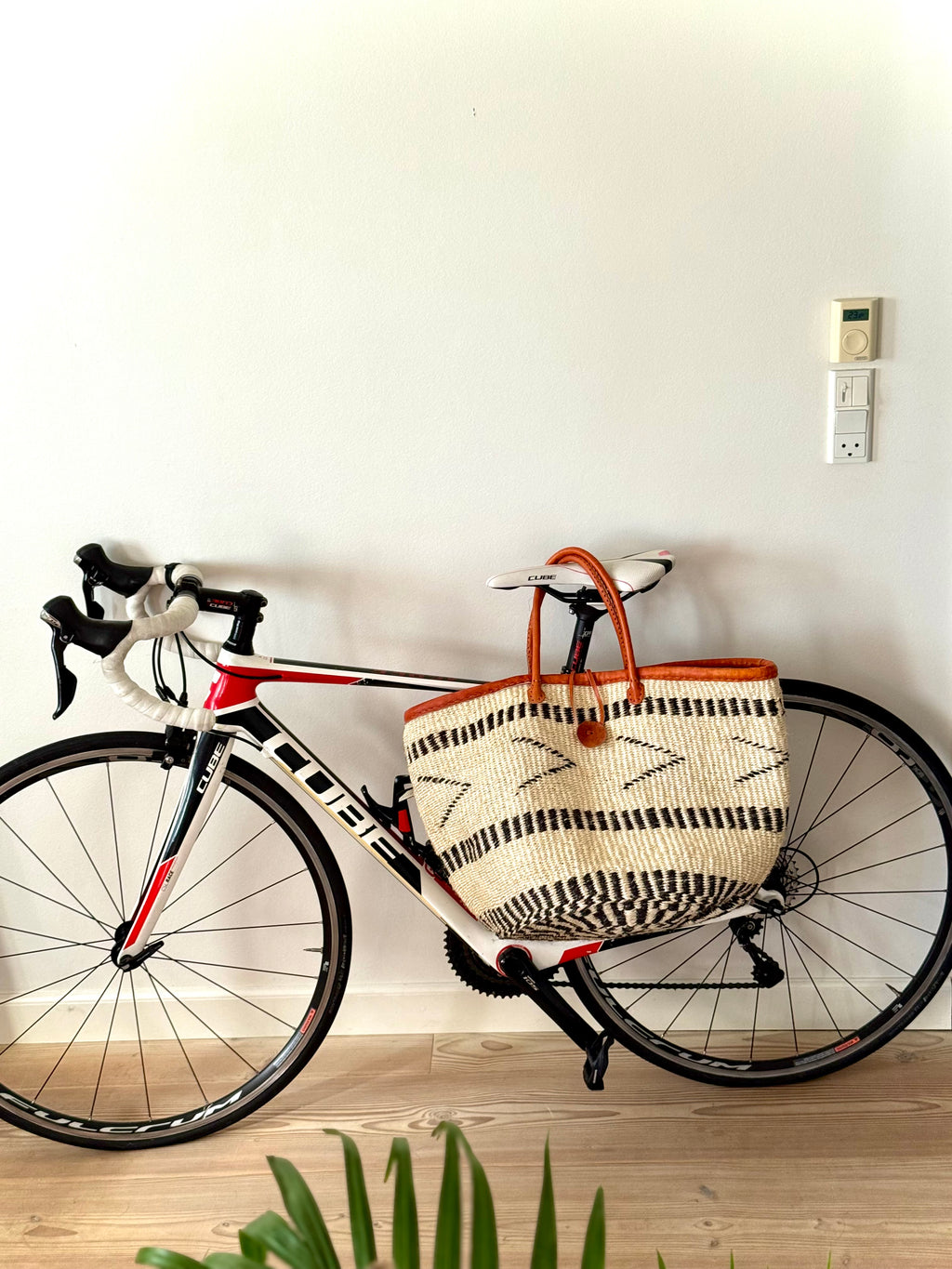 Bicycle with a woven basket against a white wall