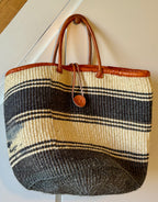 Woven bag with striped pattern and brown leather handles on a white background